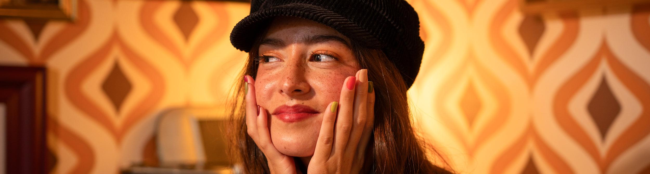Mujer con uñas de colores de otoño, fondo retro, manicura moderna, estilo juvenil