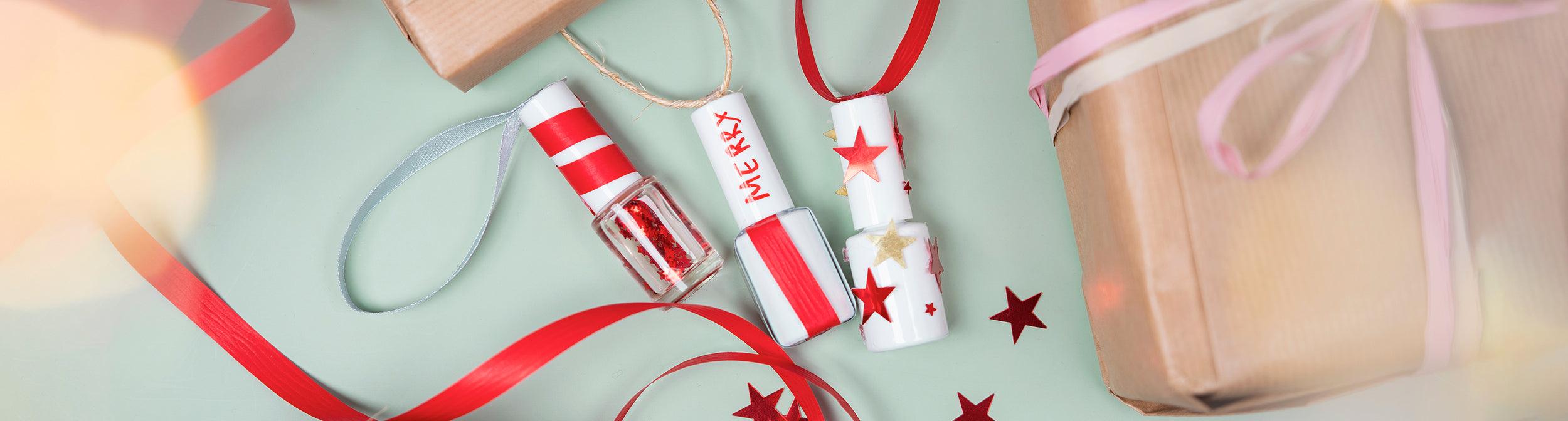 Esmaltes de uñas decorados con cintas y estrellas, junto a regalos y lazos, temática navideña