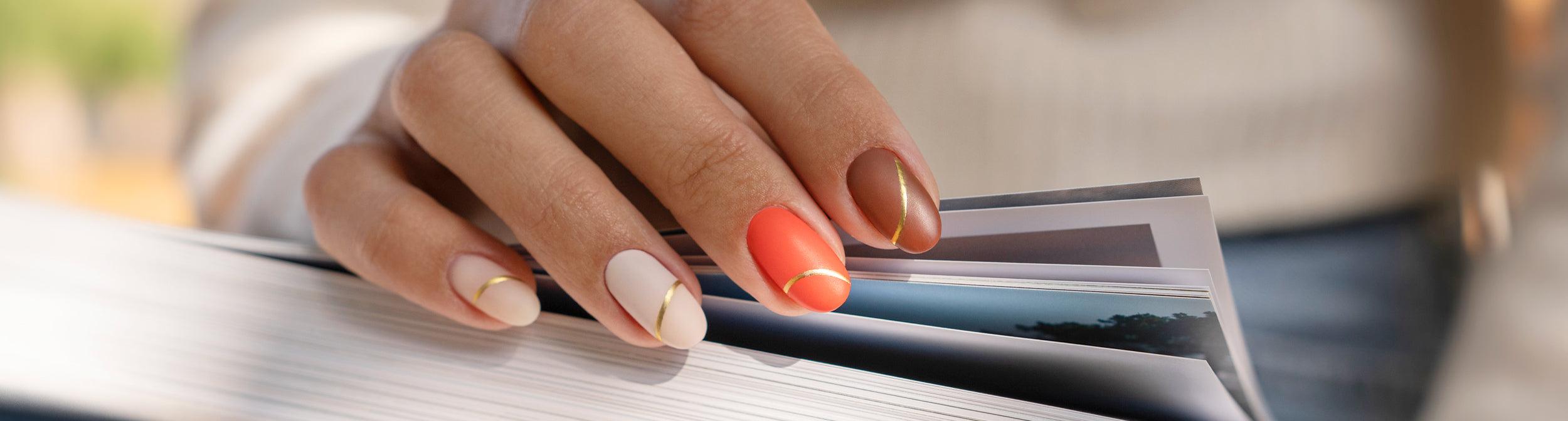 Uñas con acabado mate en tonos beige, marrón y coral con líneas doradas, manicura elegante