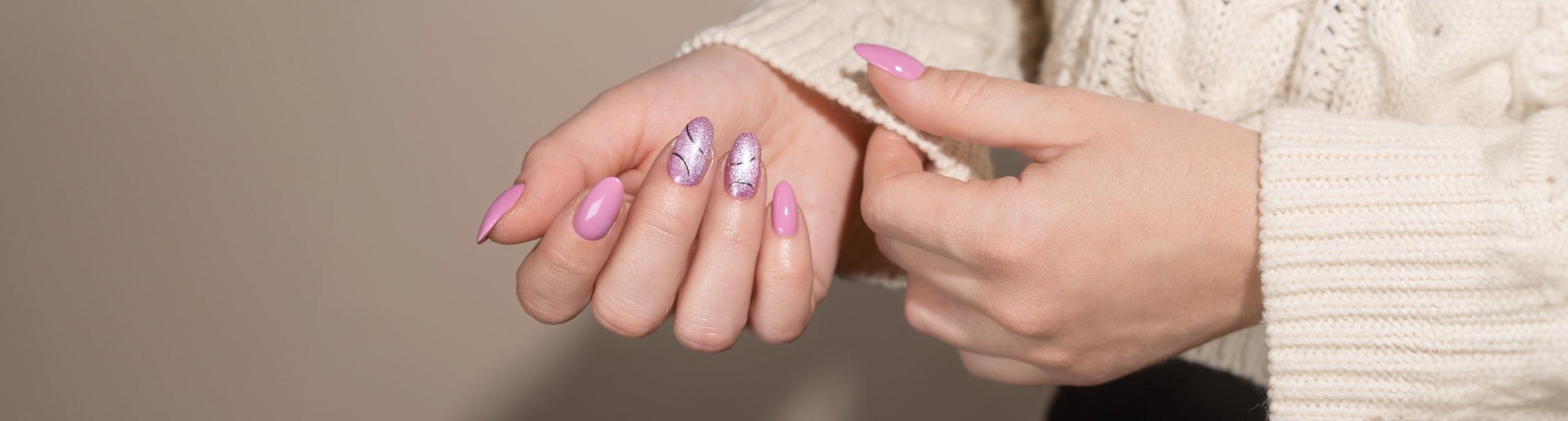 Manos con manicura rosa y diseños plateados brillantes, uñas largas y bien cuidadas