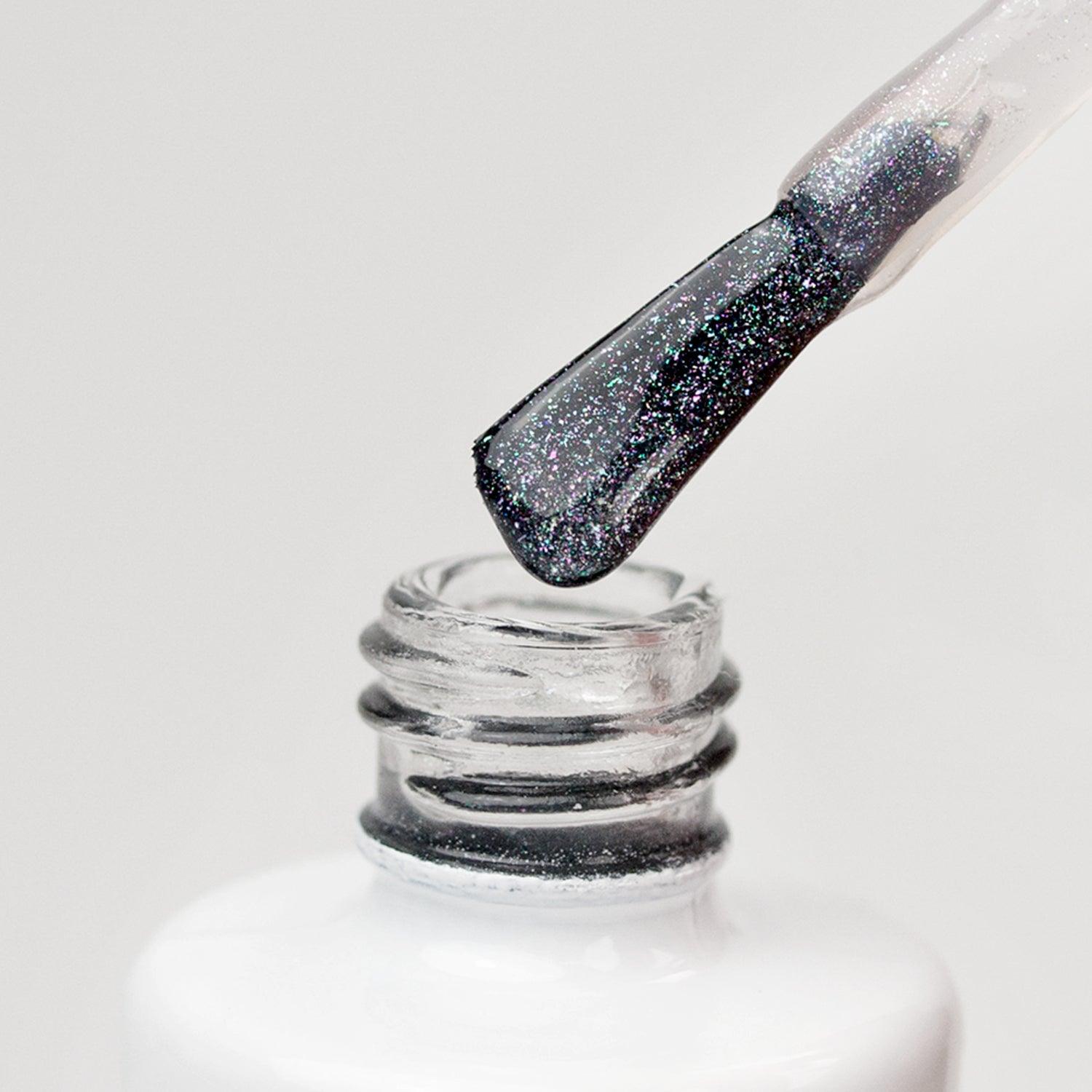Brocha de esmalte de uñas negro con purpurina entrando en un frasco blanco, manicura y nail art