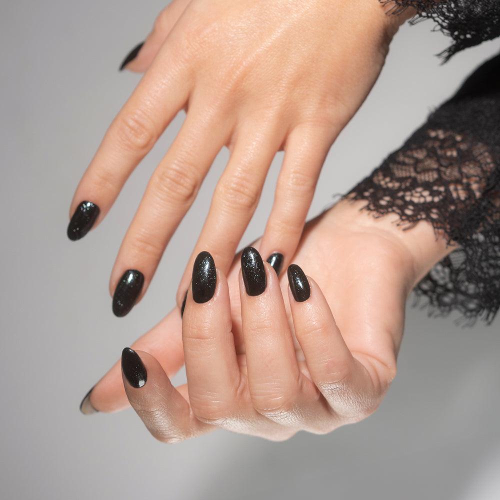 Uñas esmaltadas en negro con brillo y acabado gel, manicura elegante para mujer.