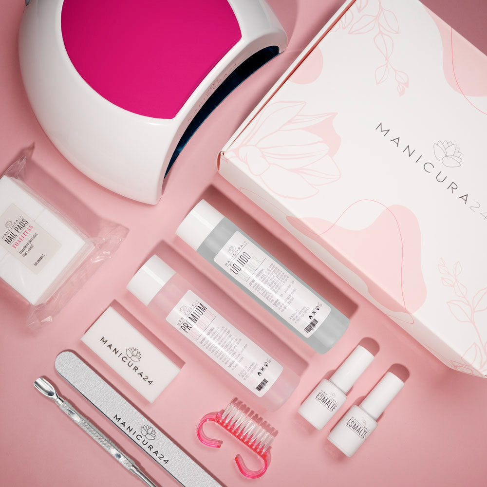 Kit de manicura profesional con lámpara LED, esmaltes, limas y accesorios sobre fondo rosa