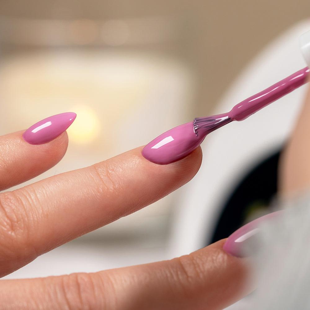 Aplicación de esmalte de uñas semipermanente rosa en manicura profesional