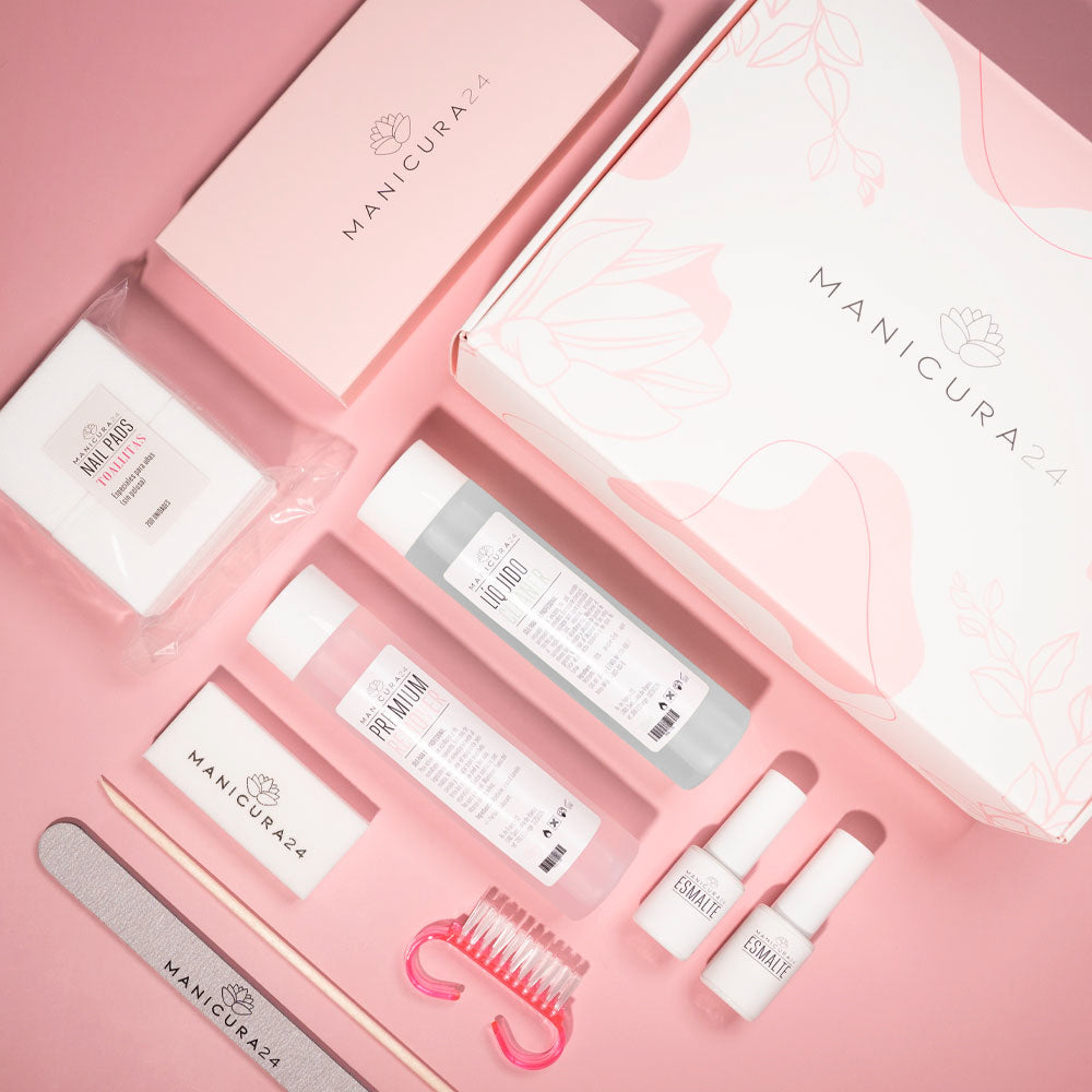 Kit de manicura sobre fondo rosa con limas, esmaltes, líquidos y accesorios.