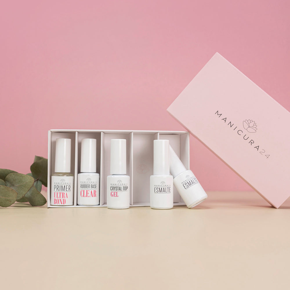 Kit de manicura con primer, base, top coat y esmaltes sobre fondo rosa, productos para uñas.