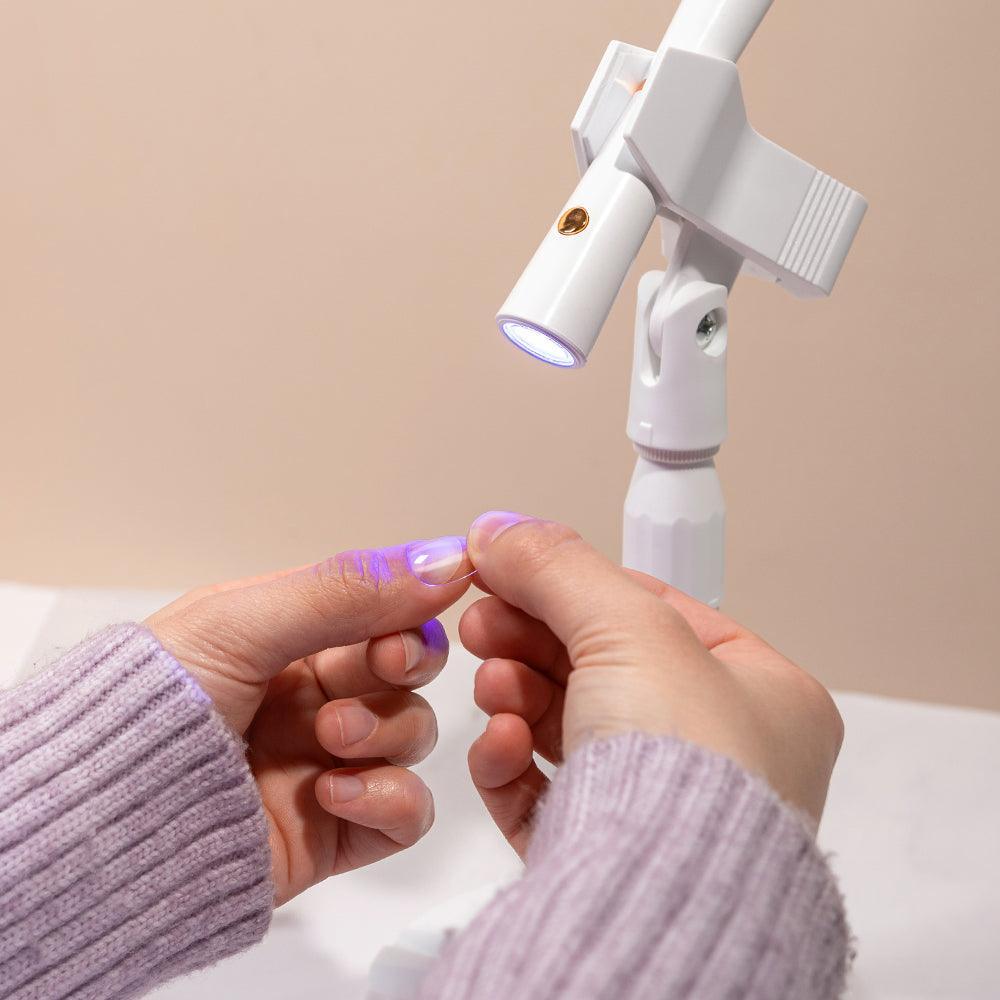 Lámpara LED UV para uñas de gel con soporte, secando manicura en manos femeninas