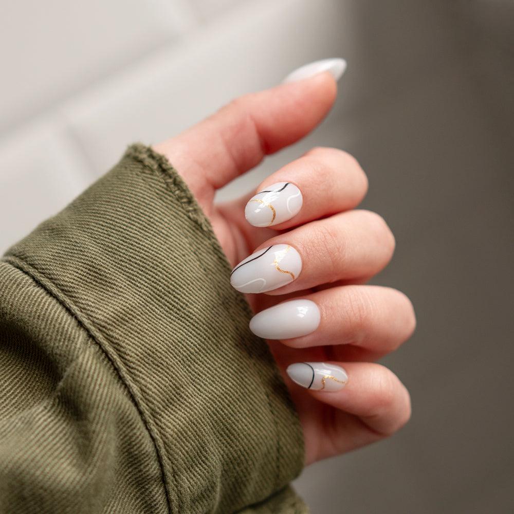 Uñas de gel soft con diseño blanco, líneas doradas y negras, manicura elegante