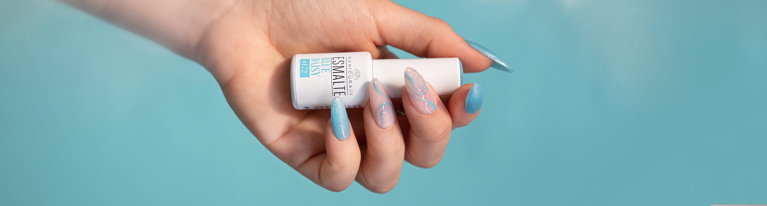 Mano con uñas decoradas en tonos azules sosteniendo esmalte de uñas semipermanente.