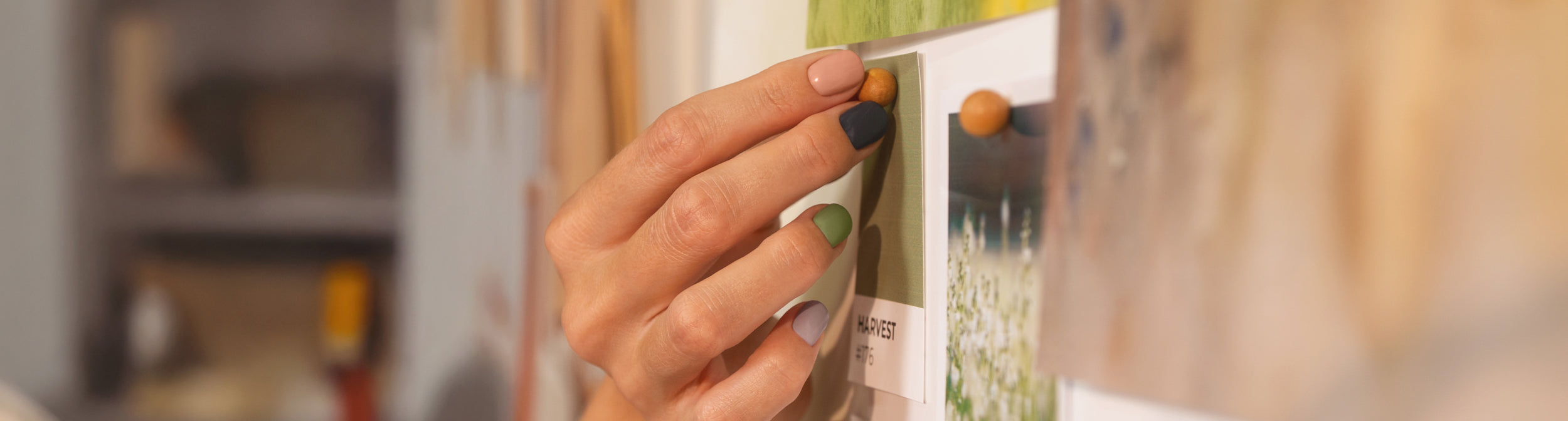 Mano con uñas pintadas en tonos otoñales sujetando imágenes en una pizarra