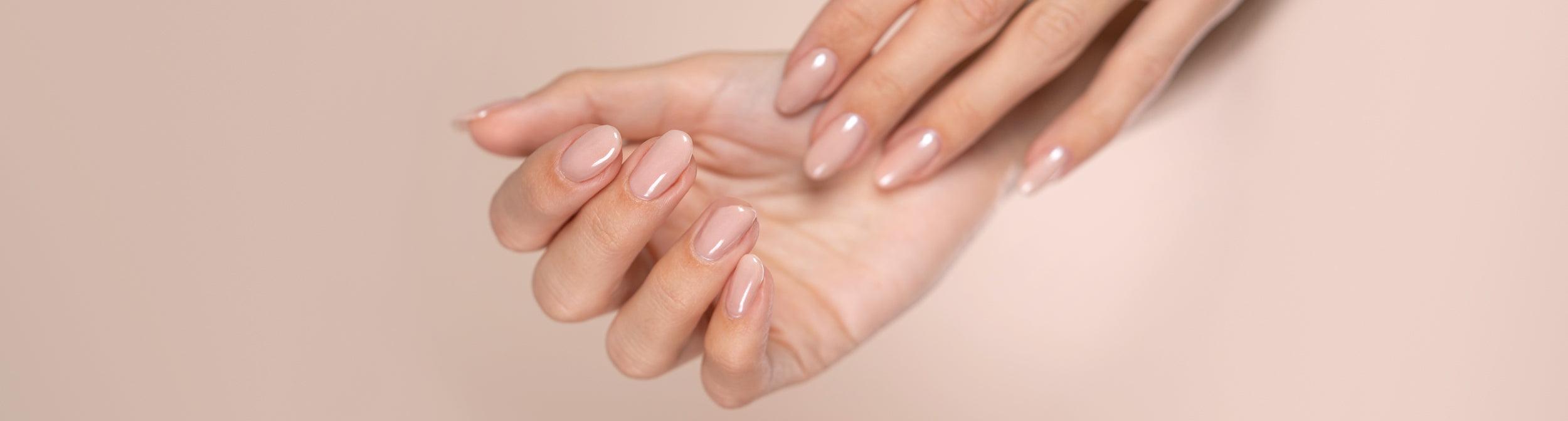 Manos femeninas con manicura francesa nude, uñas cuidadas y fondo beige, productos de manicura