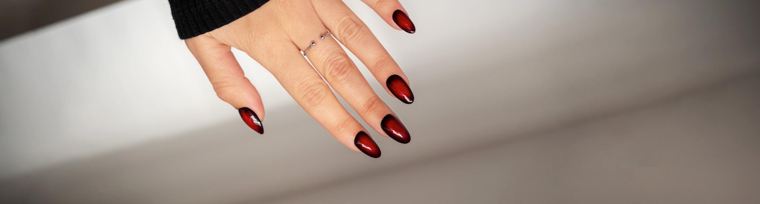 Uña con manicura aura nails en tonos rojos y negros, diseño moderno para uñas esmaltadas.