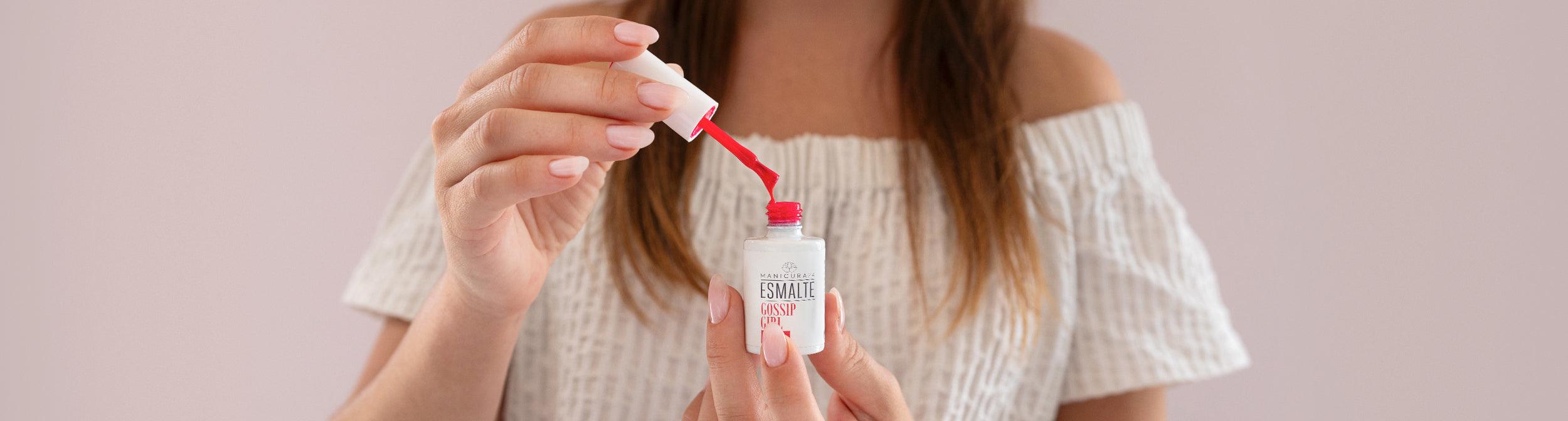 Mujer aplicando esmalte de uñas rosa, manicura profesional en casa, fondo rosa suave