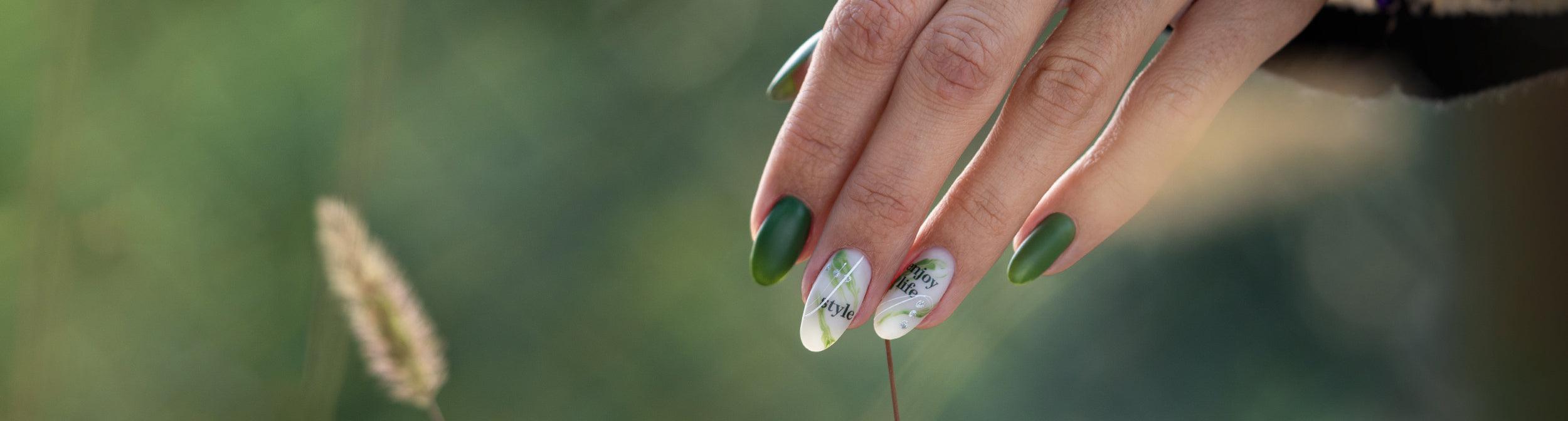 Uñas esmaltadas en verde con diseño artístico y frases, manicura moderna al aire libre