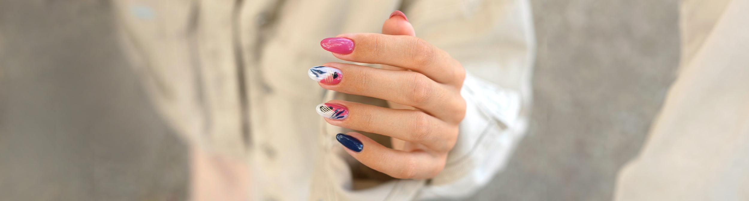 Manicura con uñas decoradas en tonos rosa, azul y estampado artístico, diseño moderno.